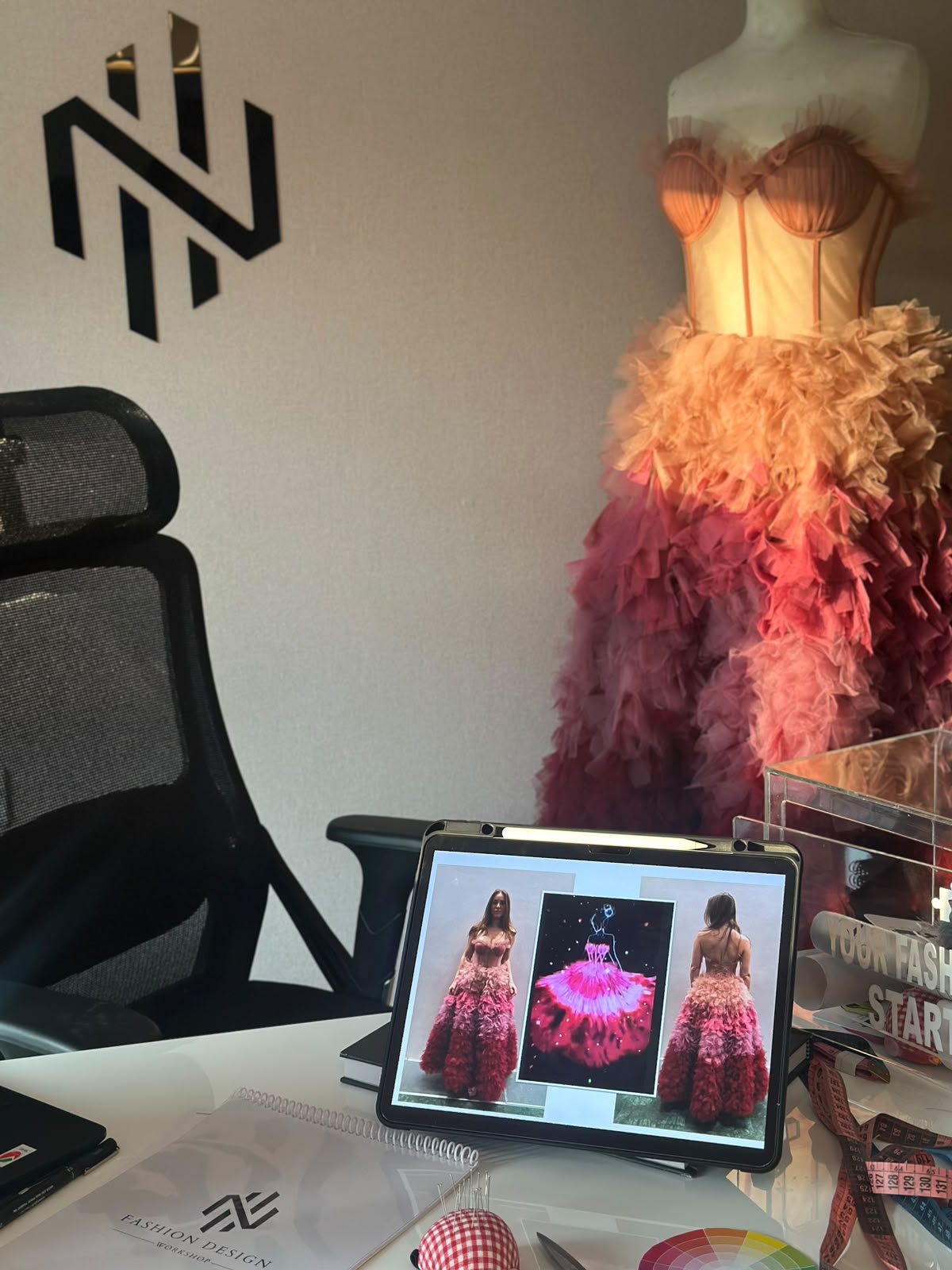 Ombré tulle gown beside a sketch on a tablet in the NH studio