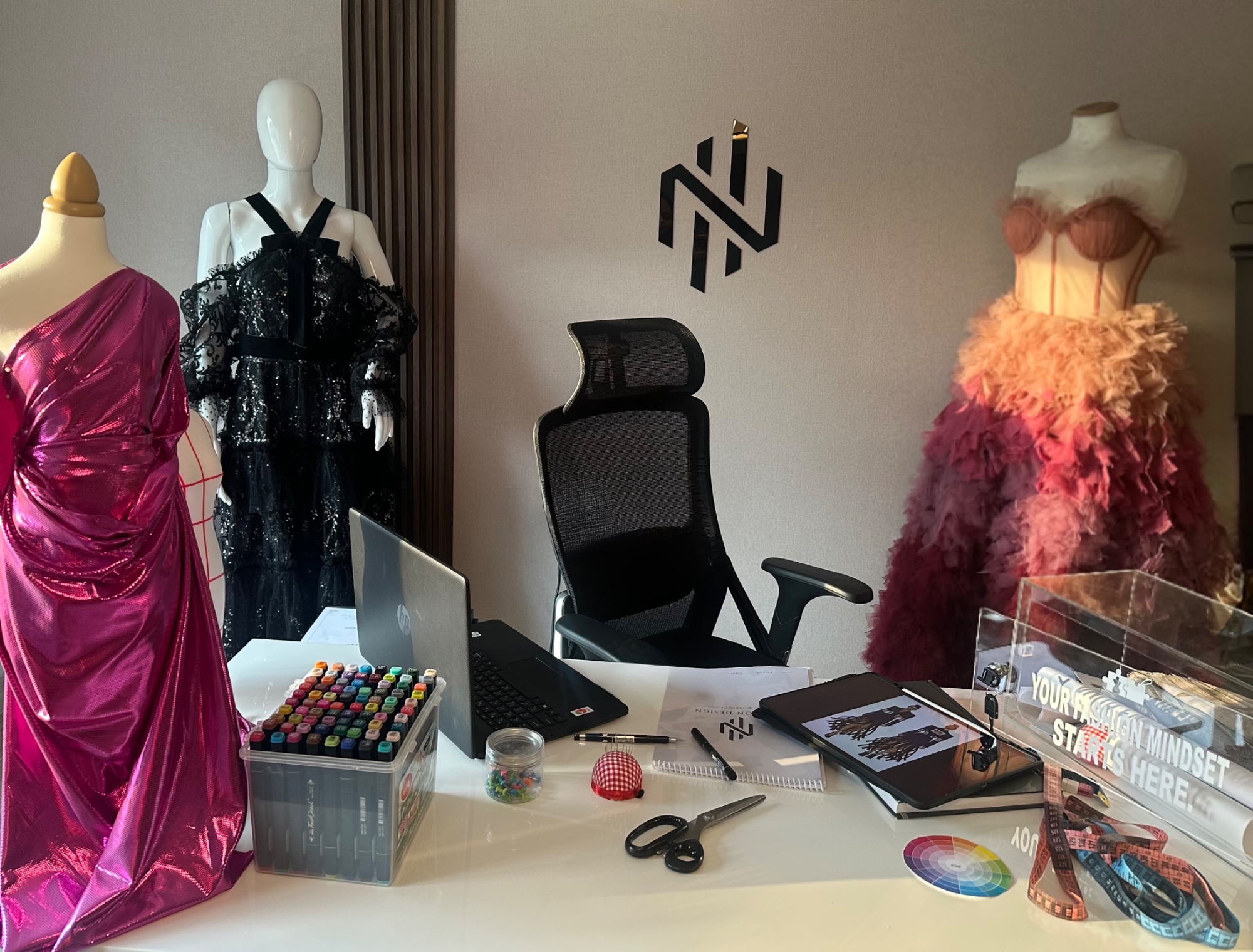 Noor Hammad's design studio with gowns, sketches and the NH logo
